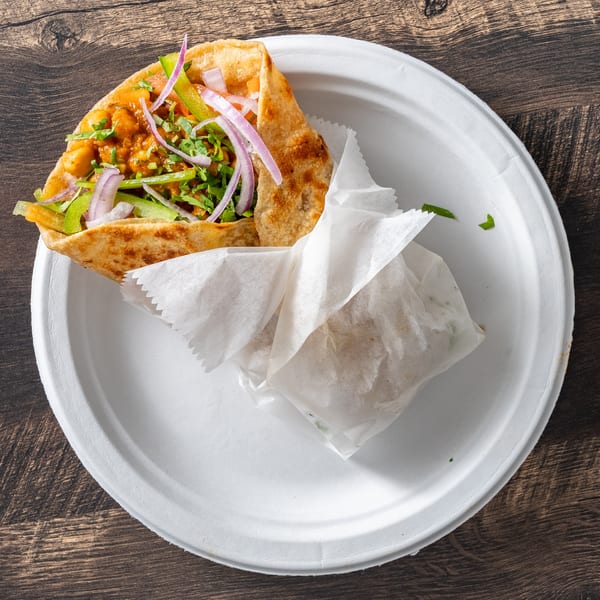 A chickpea and vegetable wrap with red onions and green peppers on a white plate.